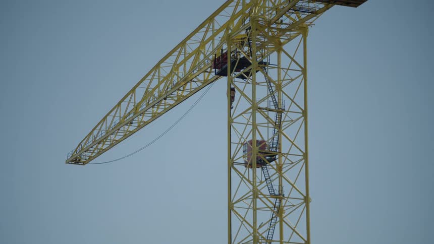 A camera view of a tall yellow crane high up in the sky