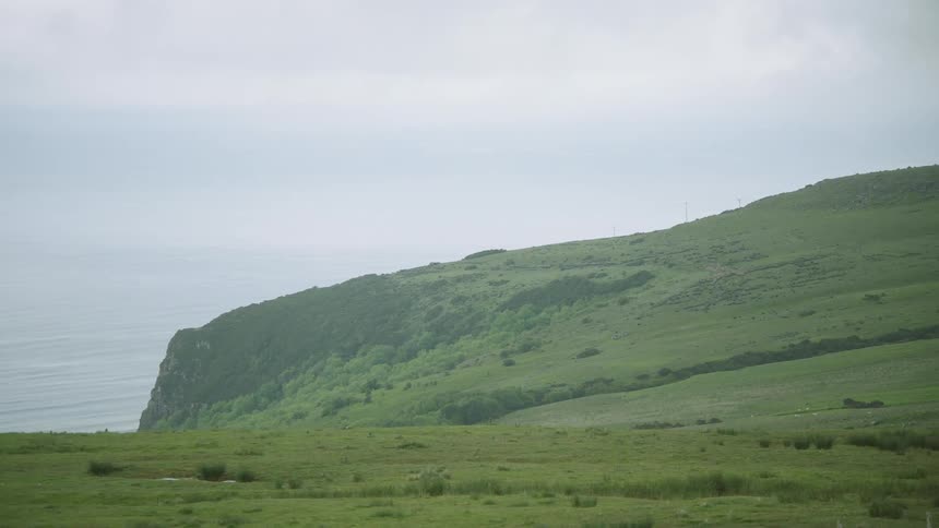 Green grass cover a mountain side coast line cliff