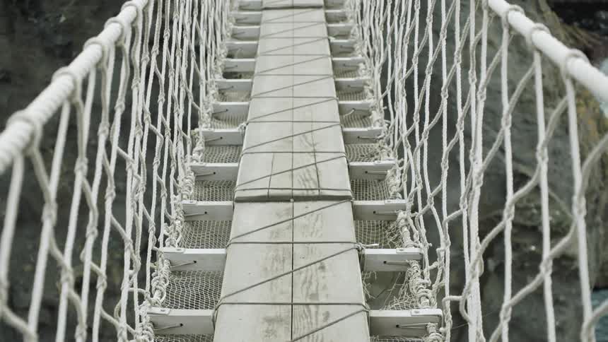The camera is moving on a rope and wooden bridge