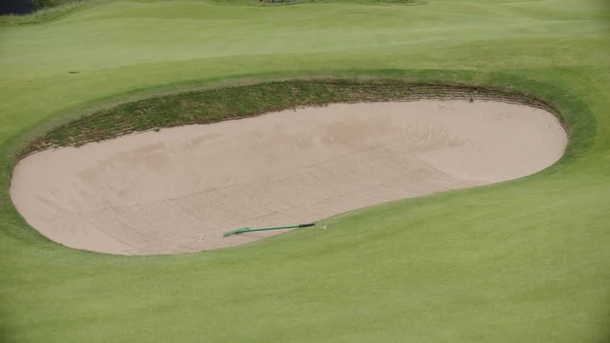 A golf club sits in an oval sand pit