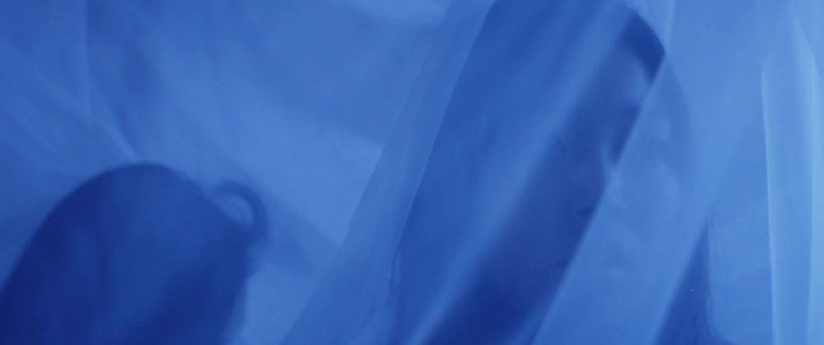 Under the transparent curtains asian women look around in the blue illuminated room