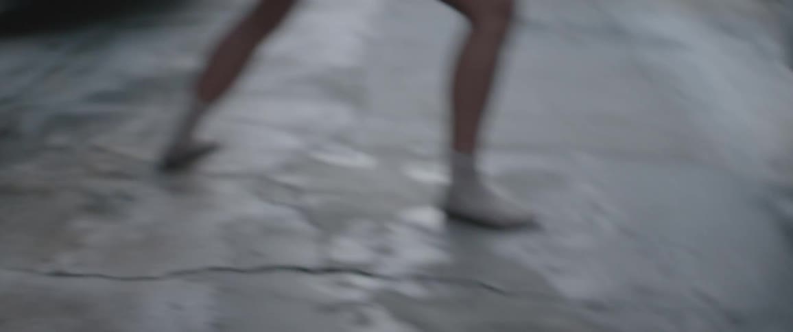 Woman dances among vehicles in parking lot