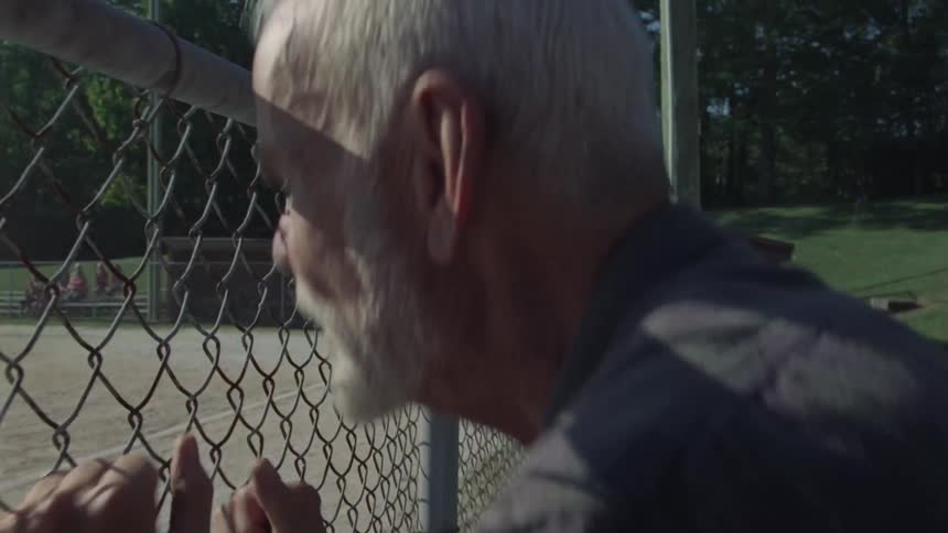 A man is watching kids play baseball outdoors