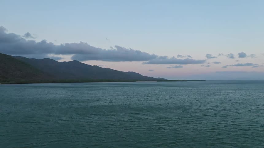 Mountainous islands on the horizon under cloudy sky after sunset