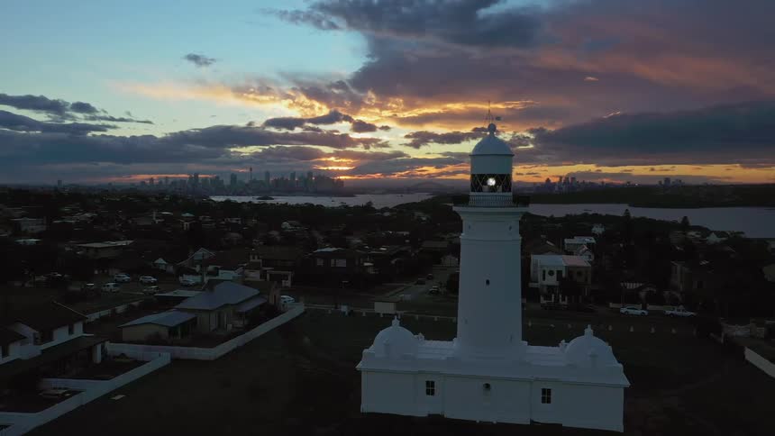 A lighthouse sits in a small town near a large urban area