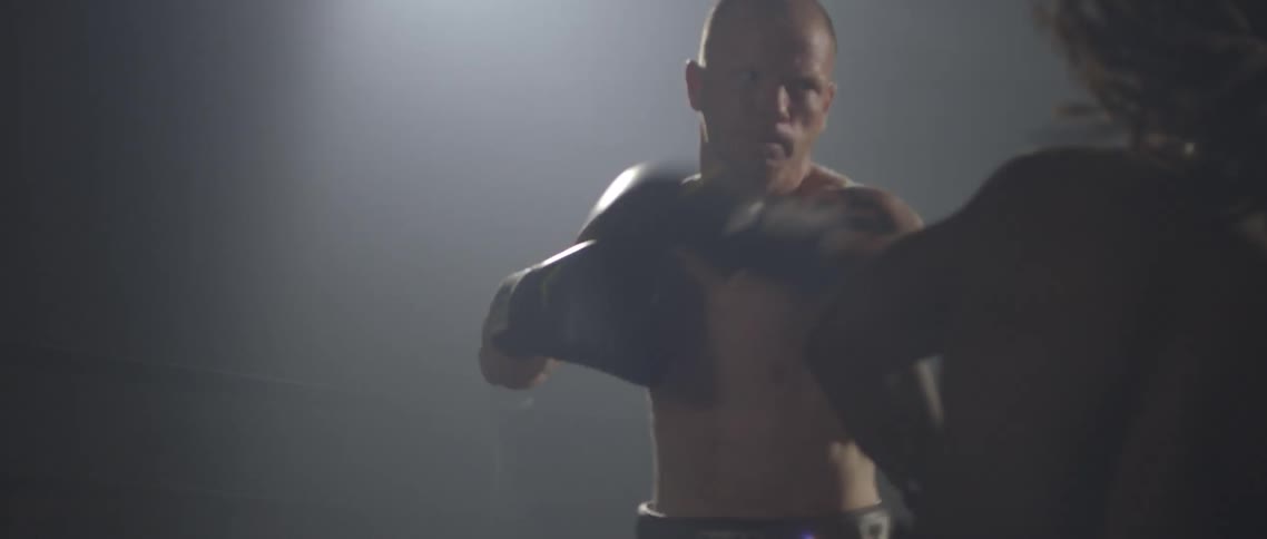 White boxer spars with black boxer and hit each other in the ringon the dark background