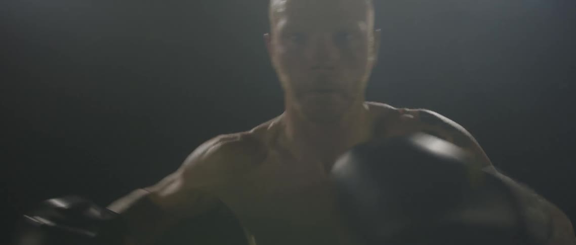 Man wearing boxing gloves shadow boxes