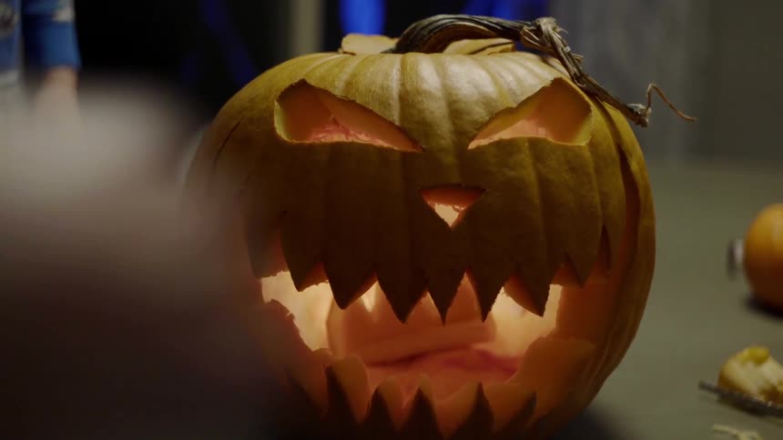 People stand around table with jack olantern
