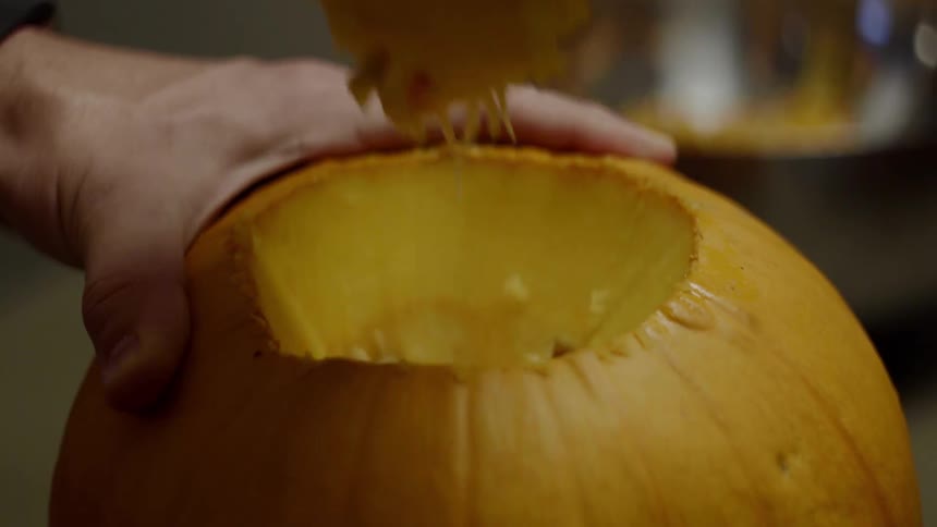 A person pulling off the top of a pumpkin