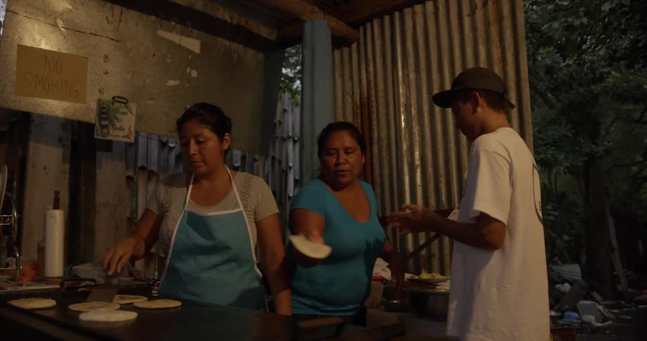 Two women and a man preparing and cooking flatbread