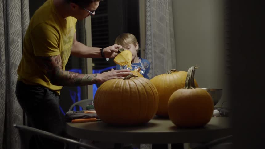 A man pulls off the top stem of a cut pumpkin