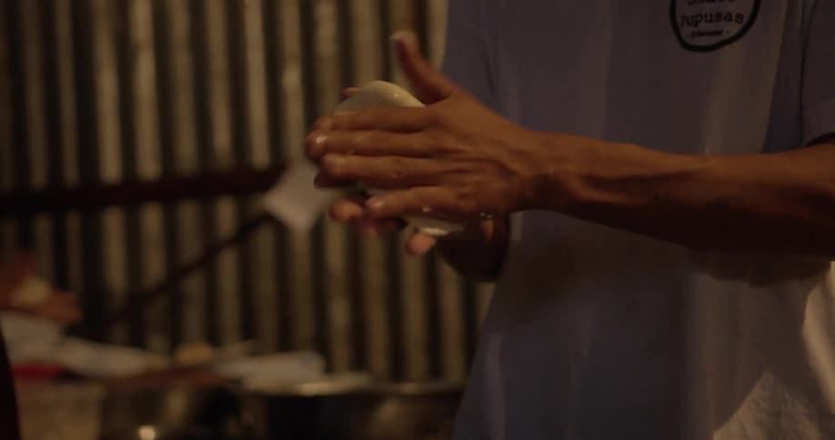 A close up shot of a man kneading and flattening wet dough