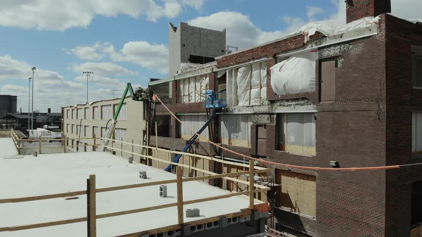 A birds eye view of an older brick building under construction on a sunny day