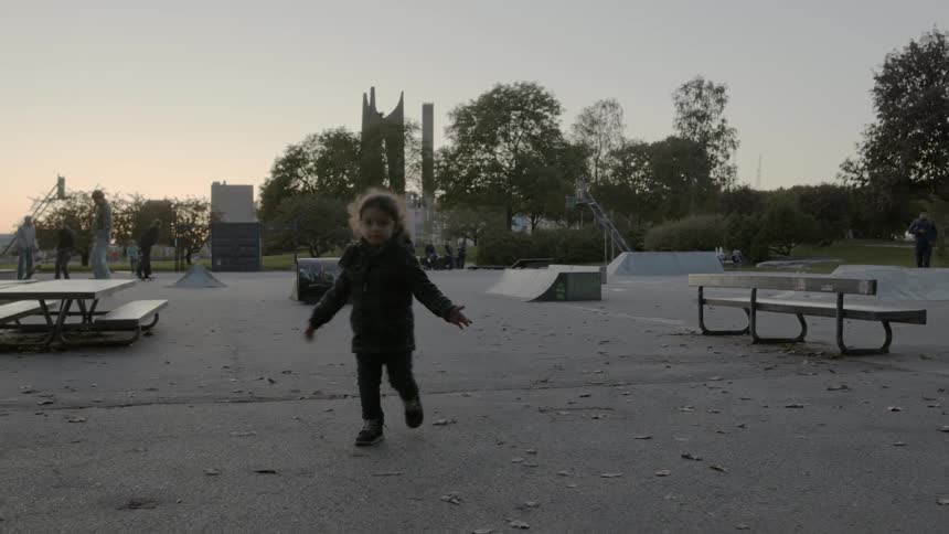 Girl wearing coat runs through picnic area