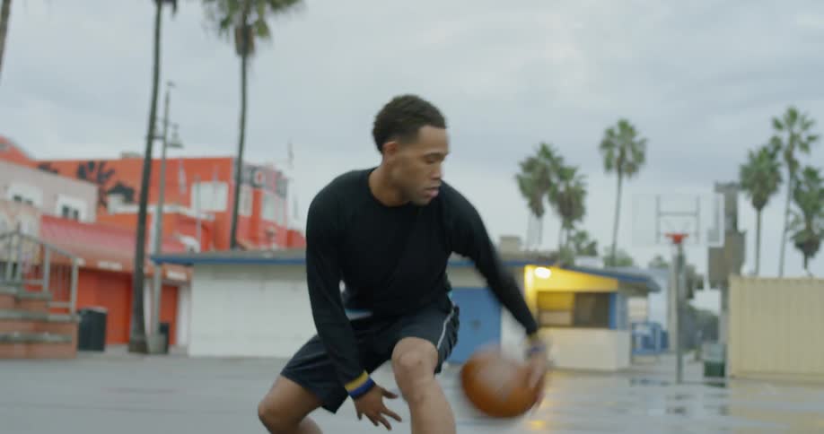 A man dribbles a basketball through his legs