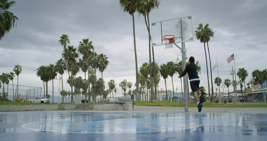 Man bounces a basketball then moves towards the hoop and takes a shot