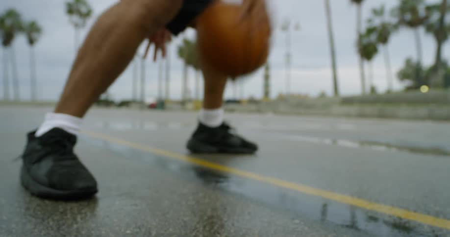 A man bouncing a basketball between his legs
