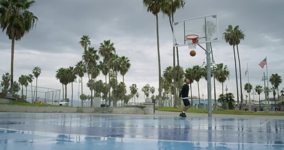 A man is dribbling the ball from the hoop