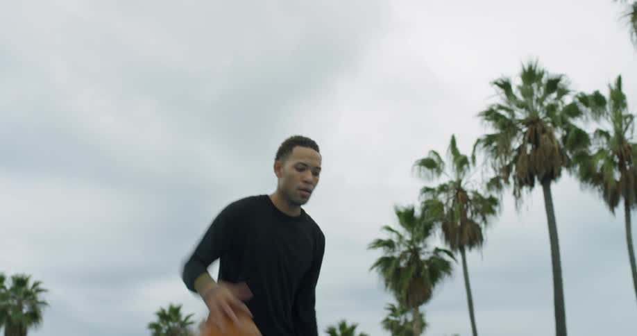 A black man dribbles a basketball and takes a shot