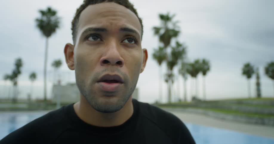 Man looks over his shoulder then up at a basket on a basketball court
