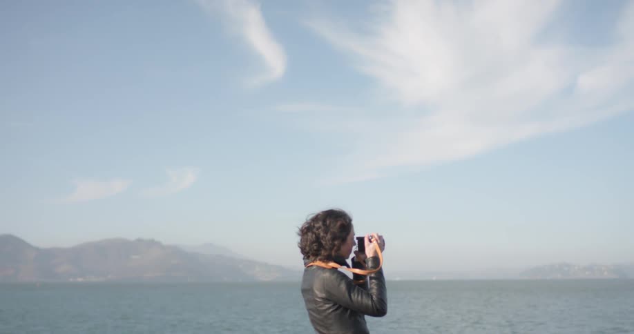 A woman takes a picture of the ocean