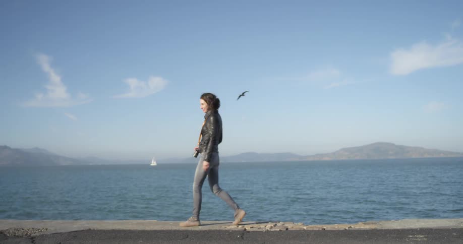A woman walking along a edge by an ocean