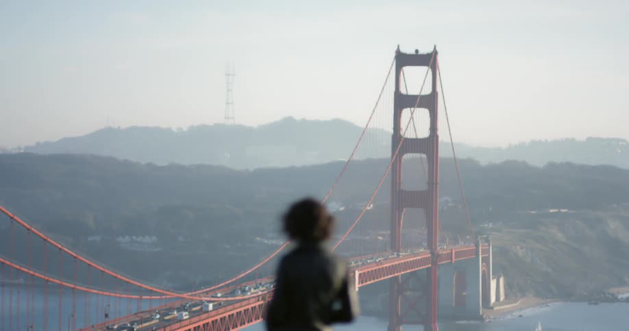Woman takes picture of suspension bridge near mountains