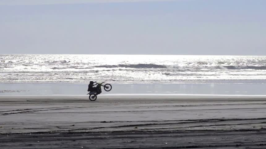 Person Riding Dirt Bike Through Rugged Terrain Under Bright Sunny Sky.
