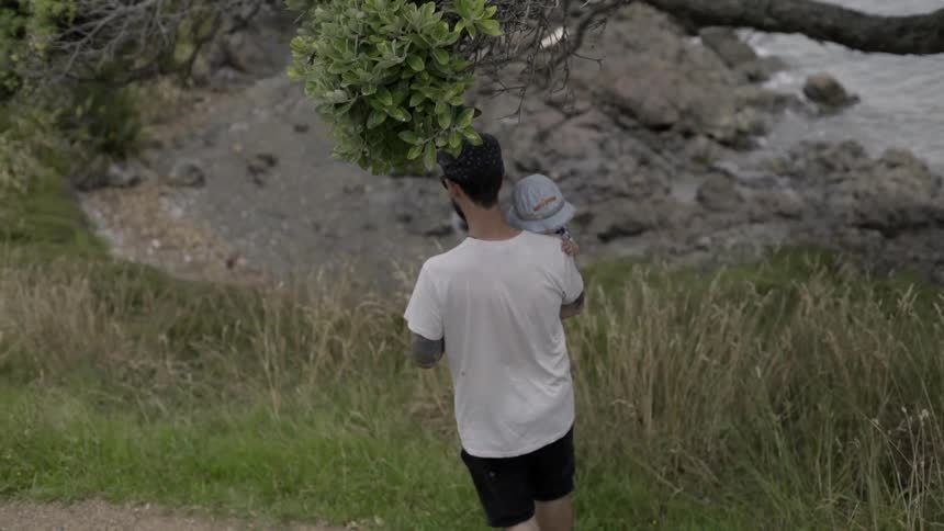 Man Holding His Kid Securely as They Descend a Hill Together, Full of Bonding.