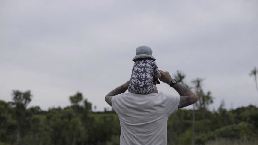 A man walks while carrying a child on his shoulders