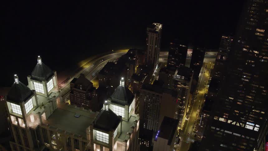 Several skyscrapers in a downtown area are brightly illuminated at night time
