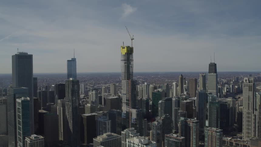 Skyscraper under construction topped with a crane in the middle of downtown city