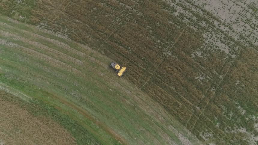 A tractor is shown harvesting crops in a vast open farm field