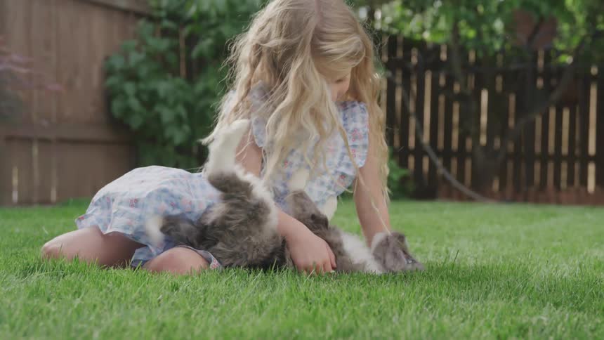 A young girl plays with a puppy in the yard