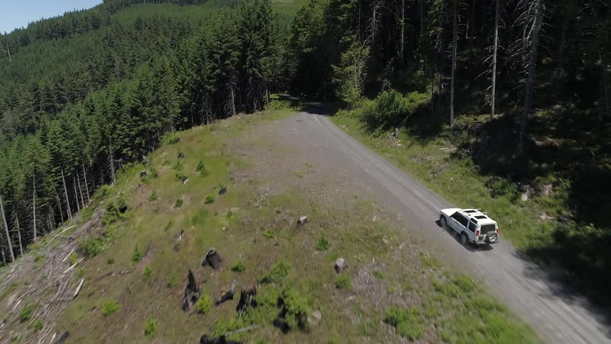 Car goes down on the mountain dirt road during daylight