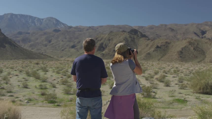 A woman takes pictures with a man standing next to her