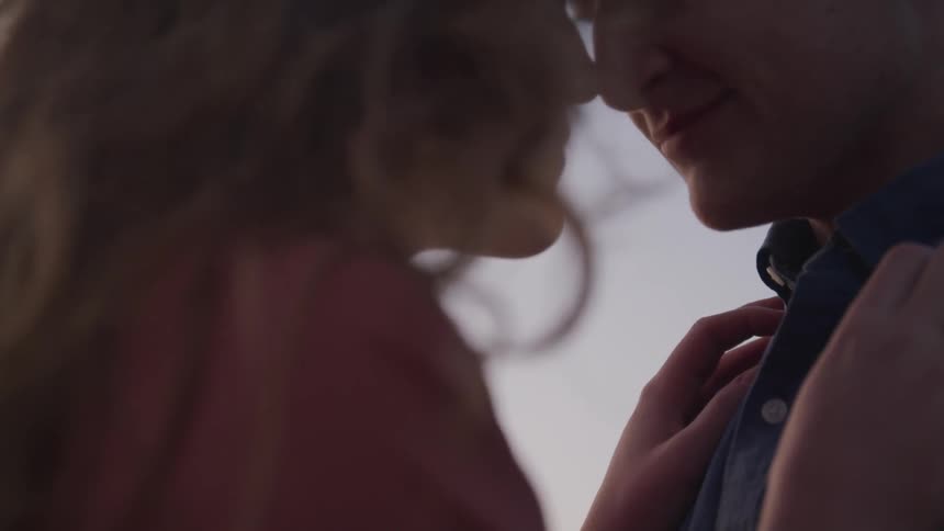 Blonde woman and man look at each other and cuddle during daylight