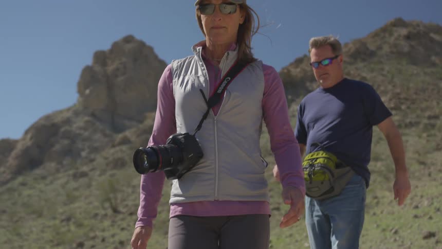 A man and woman walk across rugged terrain