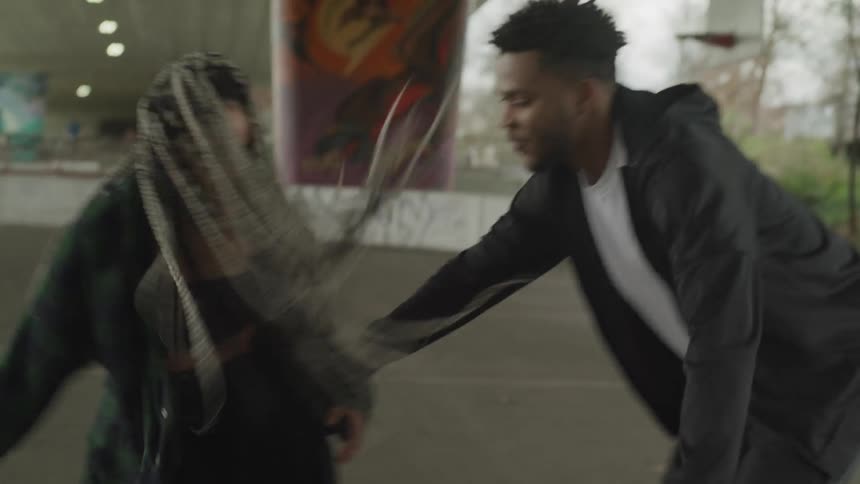 A woman and man are playing basketball outdoors