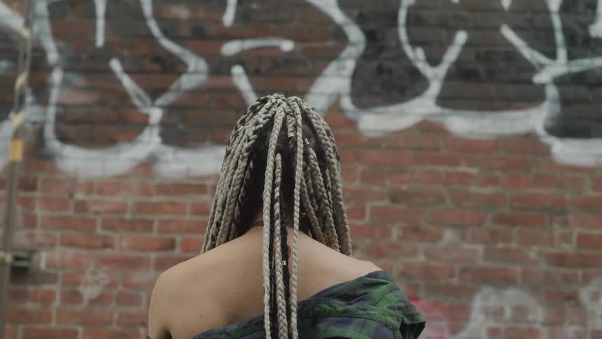 A woman is looking at a brick wall outdoors