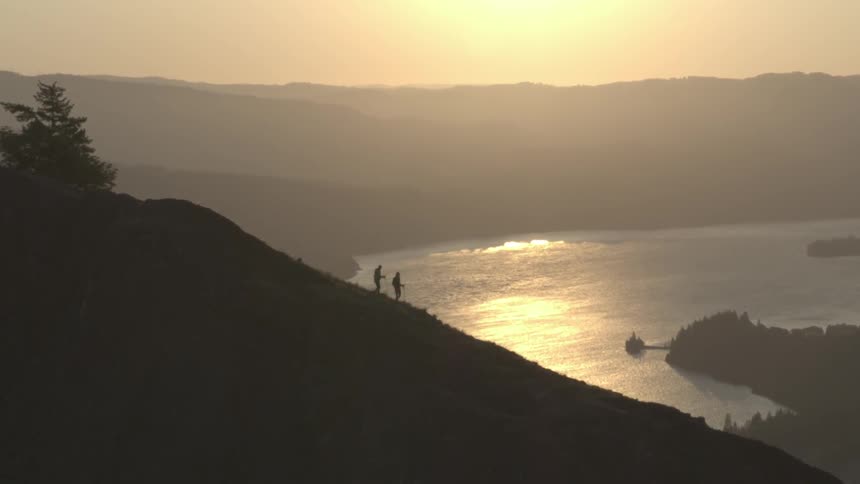 Two people walk down a large mountain cliff