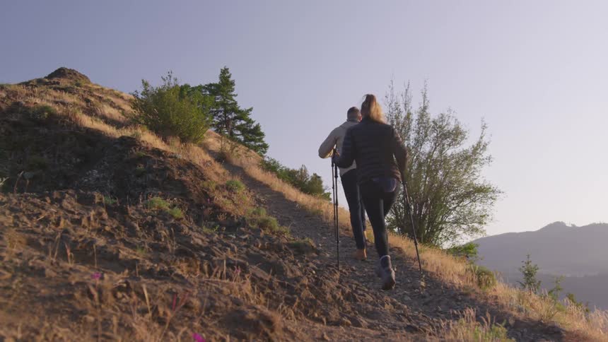 Couple hiking on rocky trail up a mountain peak