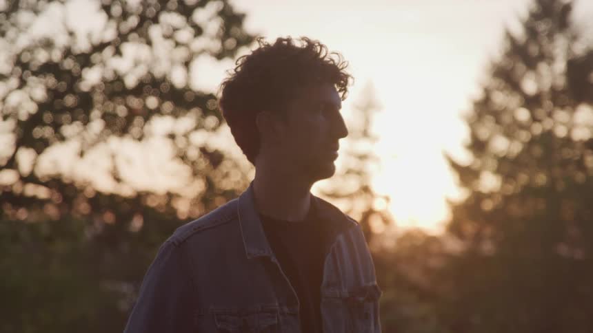 Man stands outside looking during sunset
