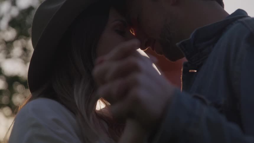 A woman and man are holding each other close outdoors