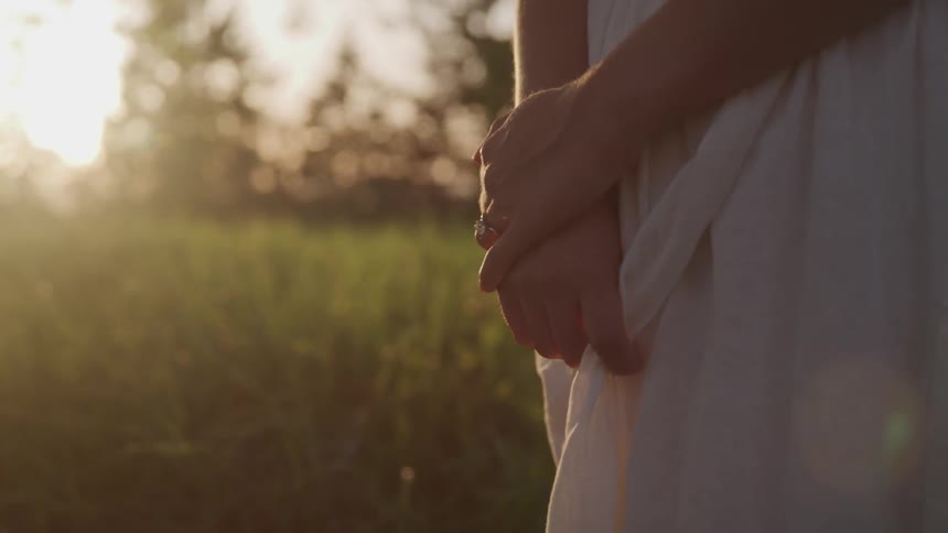 A woman standing outdoors holding her dress