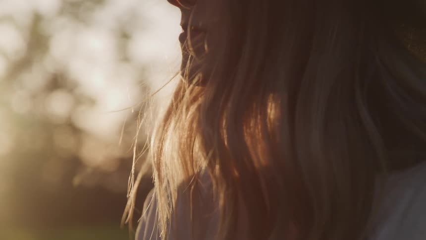 Blonde woman wearing wide hat smiles while the sun goes down