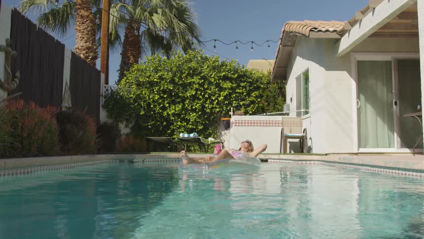 Woman relaxing on a raft in pool in the backyard