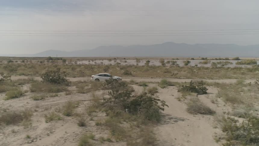 A sedan driving through desert road