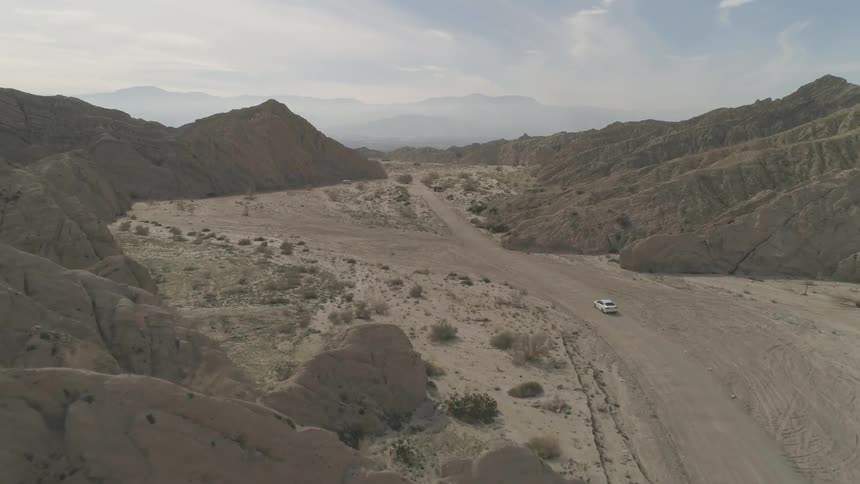 A car is driving in a desert area