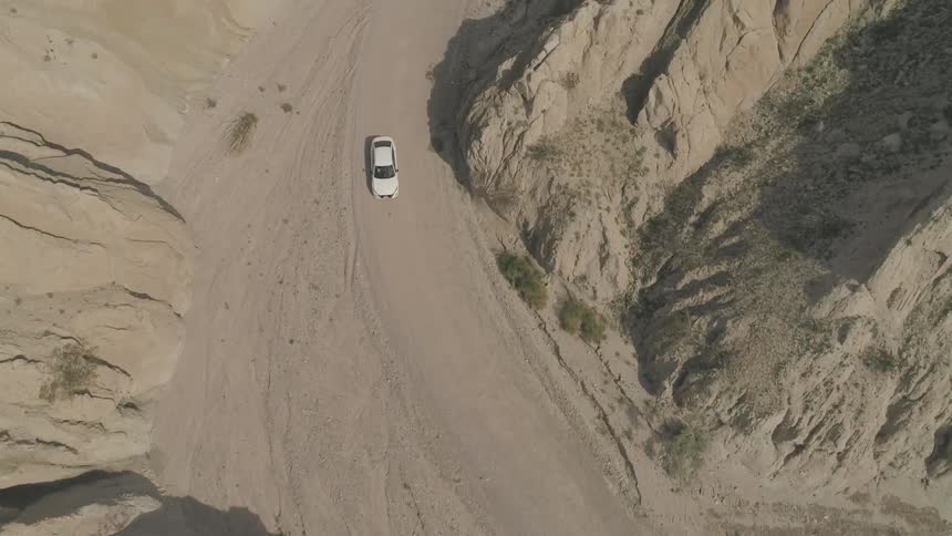 A white car drives through the desert